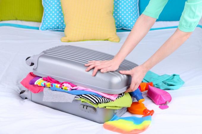 Mergina renka lagaminą ant lovos iš arti