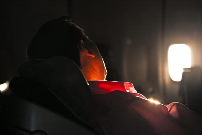 vyras miega su AN saulėtekio orlaivių sėdynės